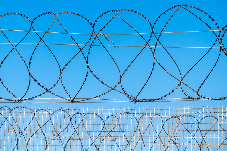 Una prisión de alambre de púas contra el cielo azul