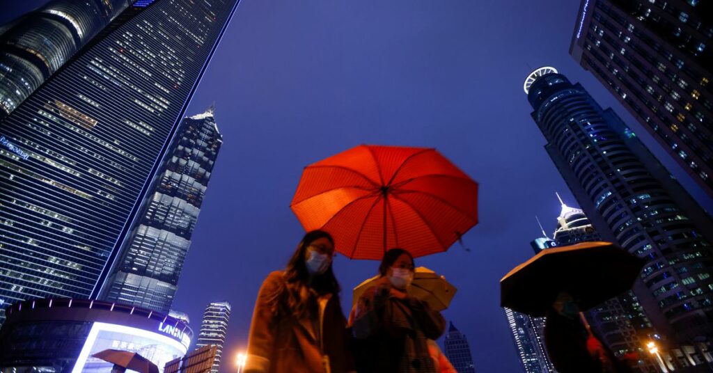 People walk with umbrellas in Lujiazui financial district in Pudong, Shanghai, on the day of the opening session of the National People