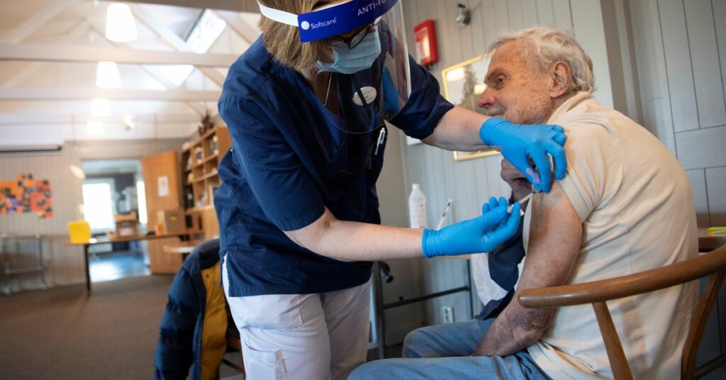 A health worker vaccinates an elderly person with Pfizer