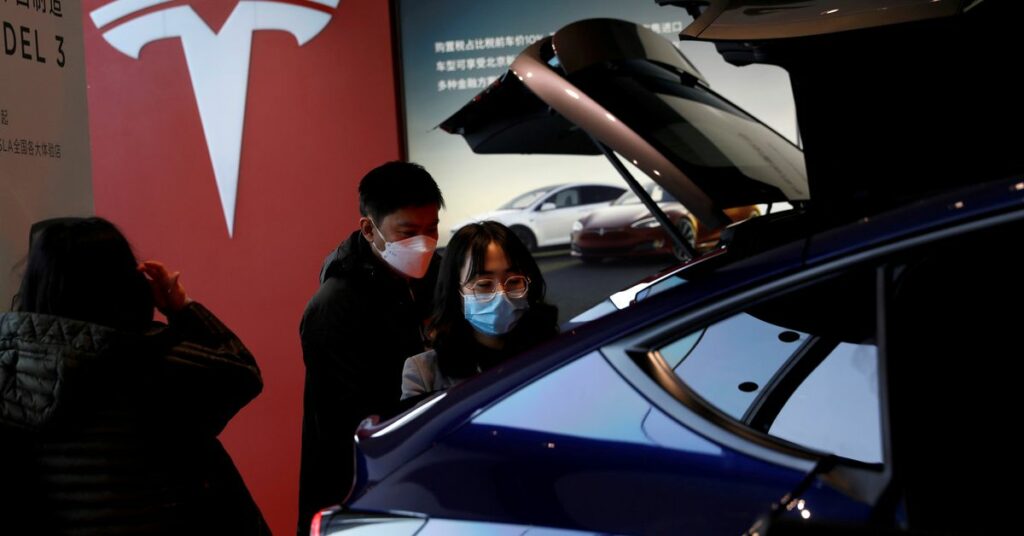Visitors wearing face masks check a China-made Tesla Model Y sport utility vehicle (SUV) at the electric vehicle maker