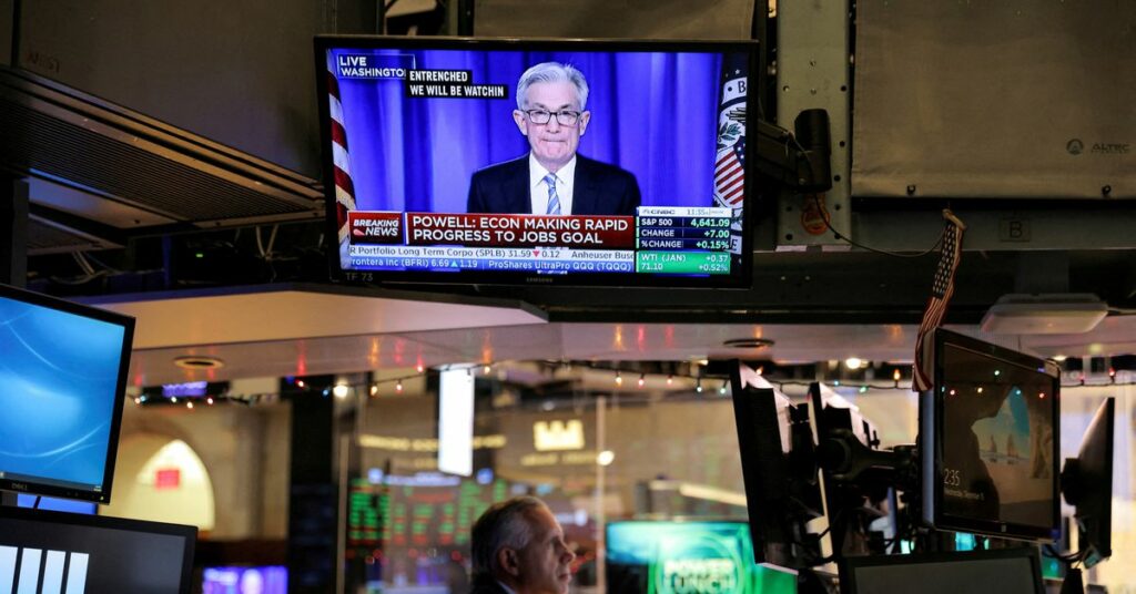Federal Reserve Chair Jerome Powell is seen delivering remarks on a screen as a trader works on the trading floor at the New York Stock Exchange (NYSE) in Manhattan, New York City, U.S., December 15, 2021. REUTERS/Andrew Kelly