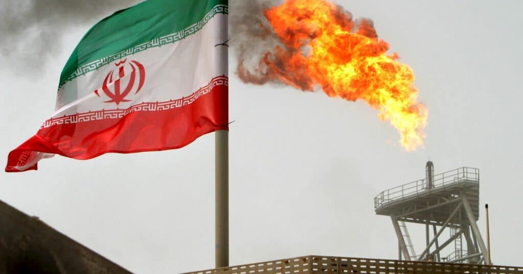 A gas flare on an oil production platform in the Soroush oil fields is seen alongside an Iranian flag in the Gulf