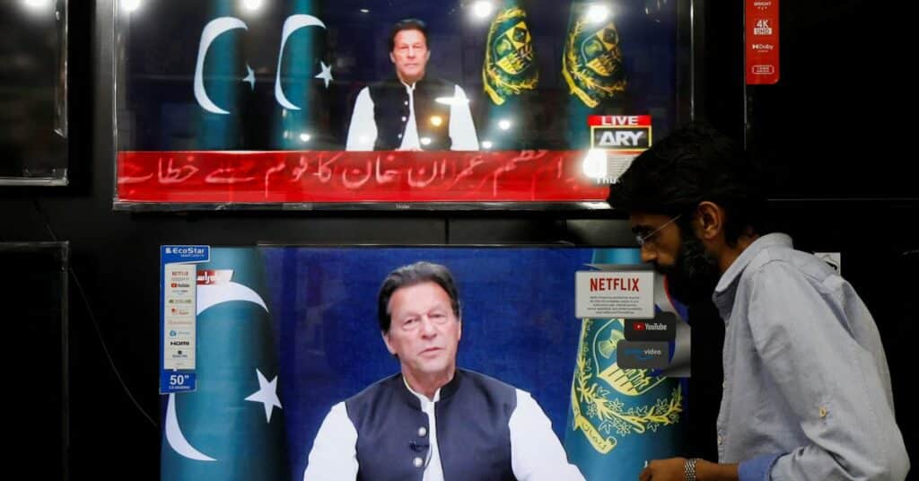 Shopkeeper tunes a television screen to watch the speech of Pakistani Prime Minister Imran Khan, at his shop in Islamabad