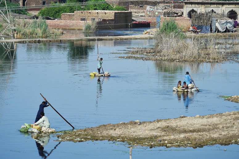 La gente usa balsas para cruzar un área inundada en Pakistán