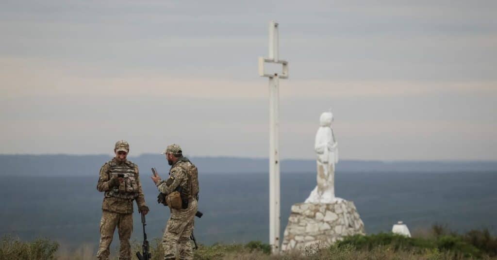Ukrainian servicemen are seen near a statue of Jesus Christ and a cross in the town of Izium