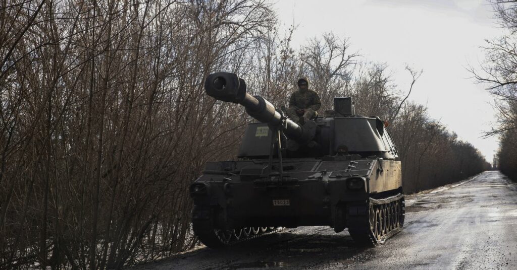 Ukrainian servicemen ride a self-propelled howitzer outside the town of Siversk