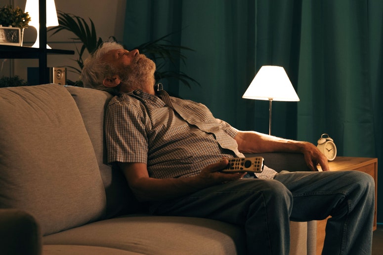 hombre durmiendo en el sofá con control remoto en la mano