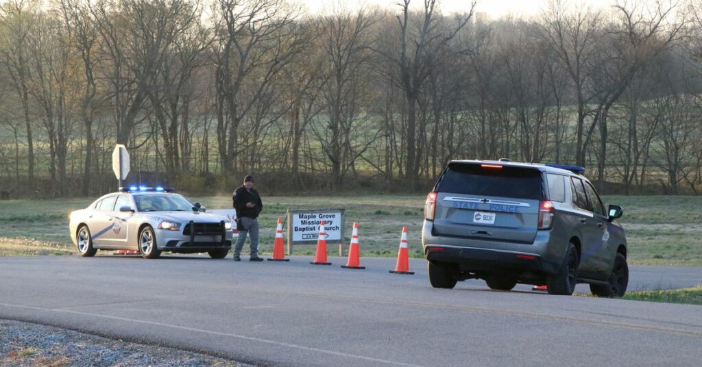 A security official stands near police cars at a site where two U.S. Army Black Hawk helicopters crashed in Kentucky